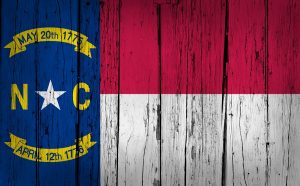 North Carolina grunge wood background with North Carolinian State flag painted on aged wooden wall.