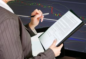 Lady wearing a business suit with a clip board staring at a financial statement during an audit. 